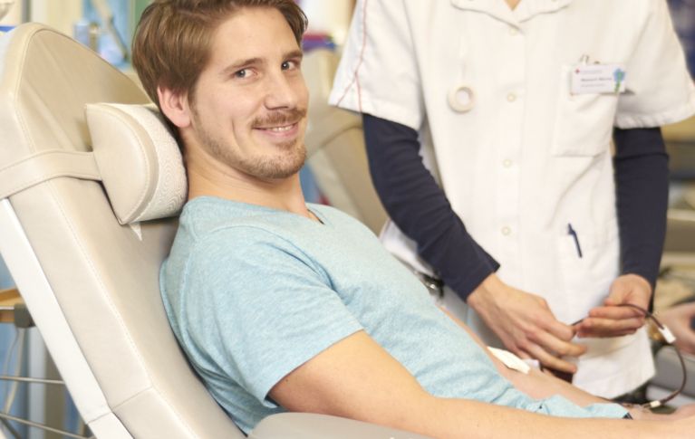 Junger Mann liegt auf einer Liege und spendet Blut