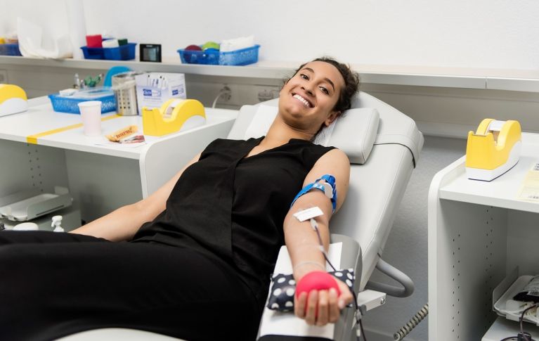 Young woman lying smiling on a blood donation stretcher.