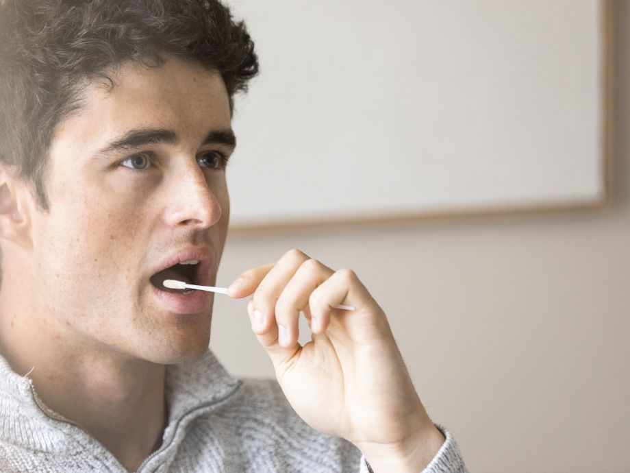 A young man takes a cheek swab for blood stem cell donation.